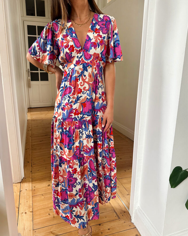 Craquez pour notre nouvelle robe Arya et ses couleurs d’été ! Le modèle parfait pour un look décontracté avec des sandales ou avec une jolie paire de talons pour un style plus élégant ! Robe longue à motifs fleuris violet, corail, fuchsia et bleu. Manches courtes Joli décolleté V avec empiècement sous poitrine Jolies découpes au niveau des hanches Fente sur le devant Fabrication Française