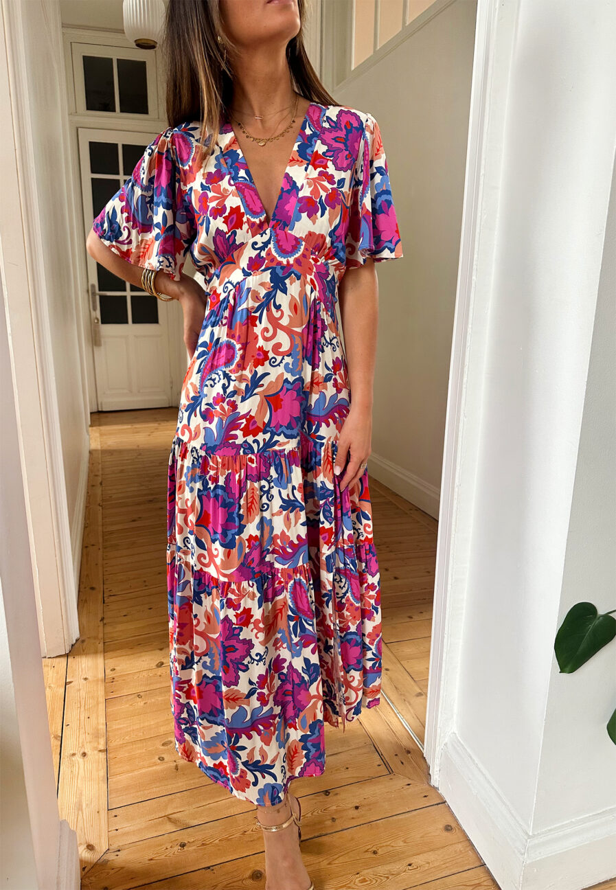 Craquez pour notre nouvelle robe Arya et ses couleurs d’été ! Le modèle parfait pour un look décontracté avec des sandales ou avec une jolie paire de talons pour un style plus élégant ! Robe longue à motifs fleuris violet, corail, fuchsia et bleu. Manches courtes Joli décolleté V avec empiècement sous poitrine Jolies découpes au niveau des hanches Fente sur le devant Fabrication Française