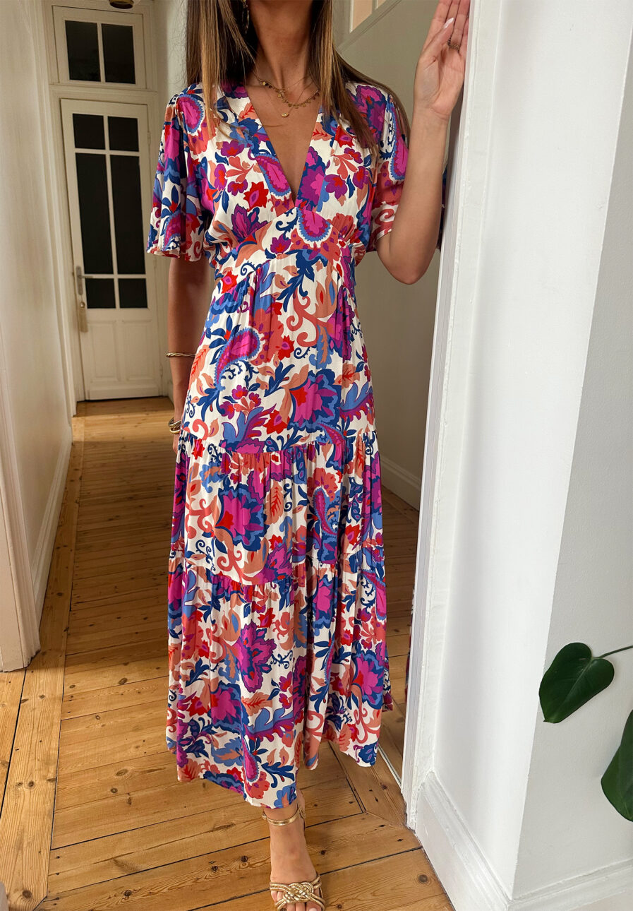 Craquez pour notre nouvelle robe Arya et ses couleurs d’été ! Le modèle parfait pour un look décontracté avec des sandales ou avec une jolie paire de talons pour un style plus élégant ! Robe longue à motifs fleuris violet, corail, fuchsia et bleu. Manches courtes Joli décolleté V avec empiècement sous poitrine Jolies découpes au niveau des hanches Fente sur le devant Fabrication Française