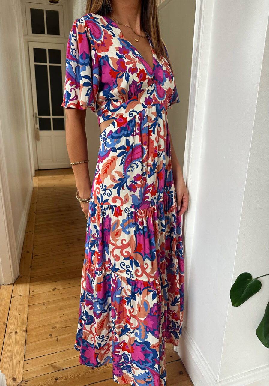 Craquez pour notre nouvelle robe Arya et ses couleurs d’été ! Le modèle parfait pour un look décontracté avec des sandales ou avec une jolie paire de talons pour un style plus élégant ! Robe longue à motifs fleuris violet, corail, fuchsia et bleu. Manches courtes Joli décolleté V avec empiècement sous poitrine Jolies découpes au niveau des hanches Fente sur le devant Fabrication Française