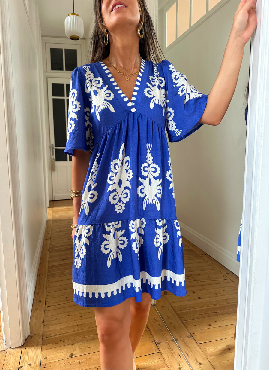 Une version plus courte et décontractée de notre fameuse robe Emma ! Parfaite pour un look de plage tout en restant féminine ! Robe courte à imprimé fleuri ethnique bleu roi et écru Décolleté en V Manches courtes Fronces sous la poitrine Elastique au niveau du dos pour un maximum de confort