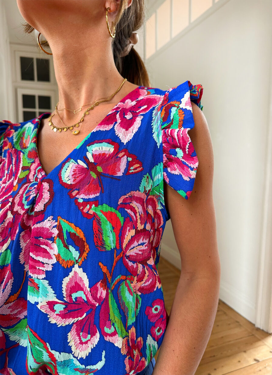 Voyez la vie en couleurs cet été ! Le top Isia sera votre parfait allié pour un look chic, bohême et estival ! Motif fleuri rose et bleu roi Joli décolleté en V et volants sur les épaules Fabrication française