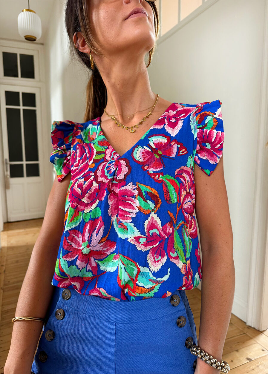 Voyez la vie en couleurs cet été ! Le top Isia sera votre parfait allié pour un look chic, bohême et estival ! Motif fleuri rose et bleu roi Joli décolleté en V et volants sur les épaules Fabrication française