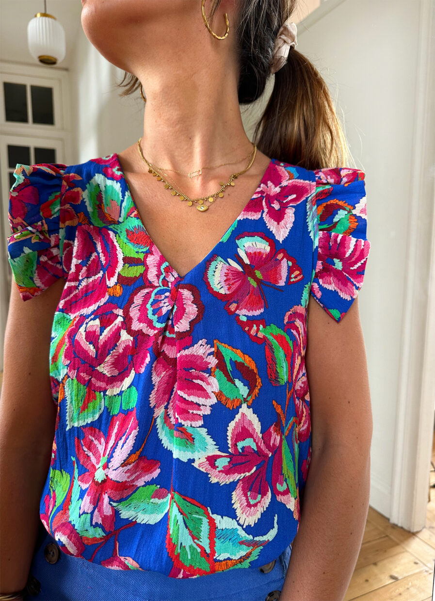 Voyez la vie en couleurs cet été ! Le top Isia sera votre parfait allié pour un look chic, bohême et estival ! Motif fleuri rose et bleu roi Joli décolleté en V et volants sur les épaules Fabrication française