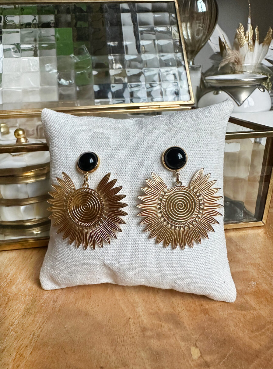 Adoptez nos nouvelles B.O Zana au style bohème chic ! B.O dorées en forme de soleil avec pierre Agathe noire Acier inoxydable Ne noircit pas Résiste à l’eau Longueur 4 cm