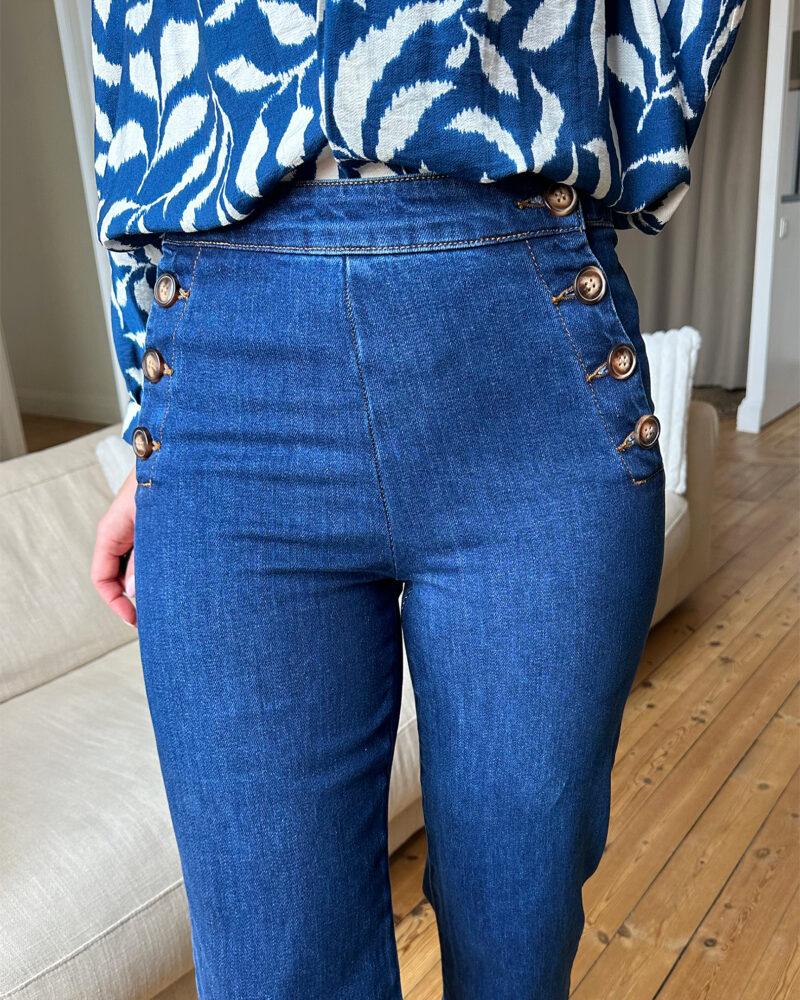 Voici MATT notre nouveau jean ultra tendance ! Modèle à ponts taille haute. Vos jambes s’allongent, c’est magique ! – Toile en coton – Boutons sur les côtés façon corne – Fausses poches passepoilées à l’arrière Il est tendance, confortable, durable et idéal pour un usage quotidien ! On adore l’associer à une grosse maille ou une jolie blouse bohème ! Ajoutez-y de jolis bijoux et un beau sac en cuir !