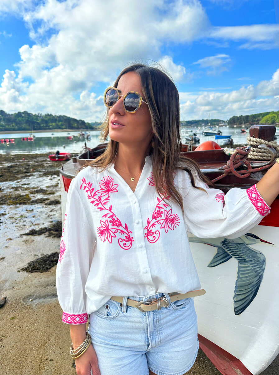 La blouse ANNA représente l’élégance et la féminité grâce à ses somptueux détails en broderie fuchsia. Ses détails apporteront une touche de romantisme à vos looks. Idéale à porter avec un jean ou un short taille haute. Col mao avec joli décolleté V Modèle boutonné sur l’avant Détail de broderies fuchsias sur l’avant et sur les manches Manches 3/4 qui se ferment à l’aide d’un bouton