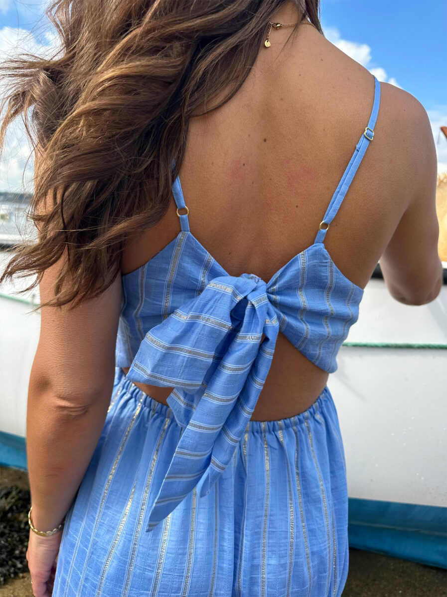 DANIELA est notre sublime robe dos nu au style bohême chic ! Son joli coloris bleu ciel et ses rayures dorées en lurex vous sublimeront. Son dos nu et son noeud délicat ajoutent une touche de sensualité à ce modèle tellement féminin. Associez-la à des sandales naturelles ou dorées et des bijoux dorés pour un look irrésistible. Taille élastiquée pour un maximum de confort Fines bretelles réglables Empiècement sous poitrine pour une silhouette flatteuse Modèle doublé