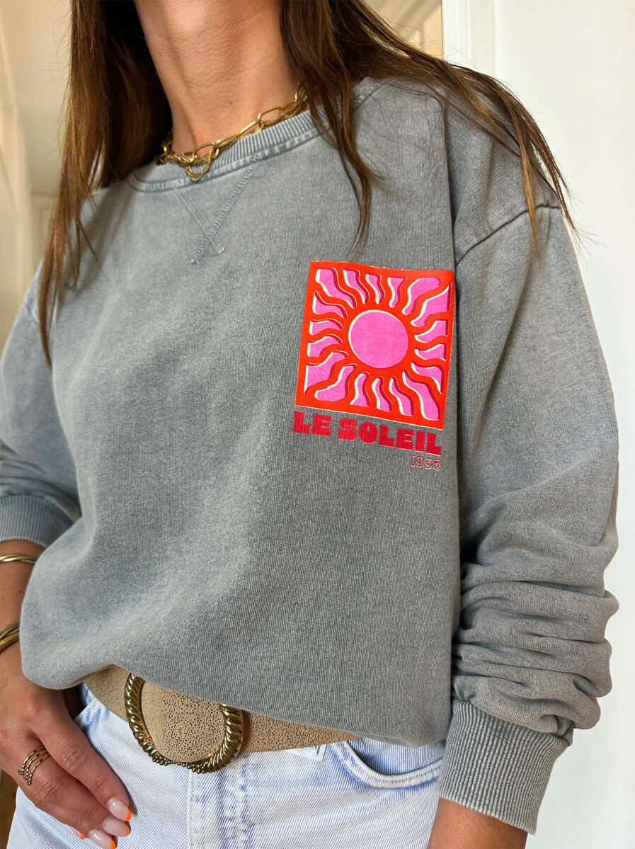 Adoptez un look ensoleillé avec nos sweats Le Soleil ajoutant une touche estivale et positive à votre tenue ! Ce sweat gris 100% coton mise sur le confort sans faire l’impasse sur le style. – Son col rond et sa coupe avec le bout des manches et le bas du sweat élastiqué en font une pièce facile à porter au quotidien. – Ce qui le rend unique ? Un logo coloré sérigraphié sur le devant, représentant un soleil accompagné de l’inscription « Le Soleil » dans des teintes chaudes de rose et d’orange. – À l’arrière, ce même motif est repris en version agrandie, avec l’inscription Le soleil. – Une pièce pleine de bonne humeur, parfaite pour faire rayonner vos looks, même les jours plus frais.