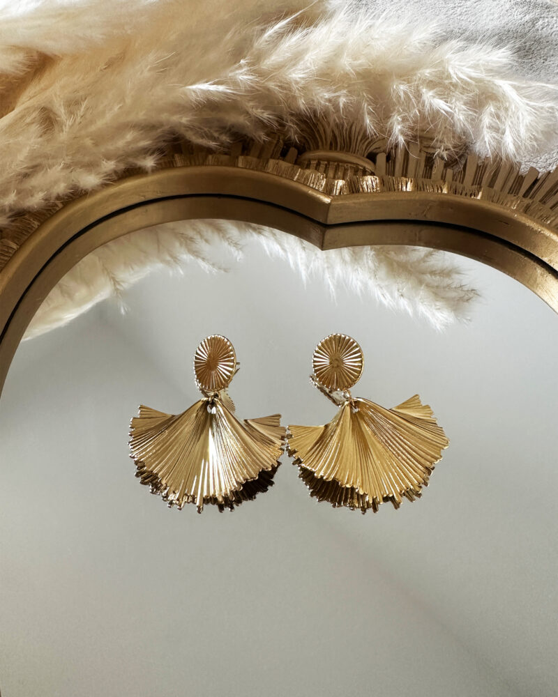 Boucles d'oreilles Morgane dorées en forme d'éventail plissé, posées sur un miroir doré.