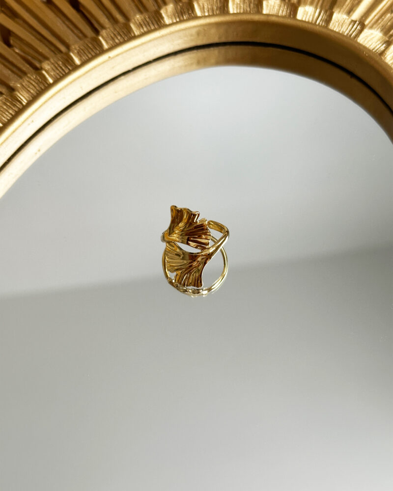 Bague ELOWEN dorée, style chic et moderne posé sur un miroir.