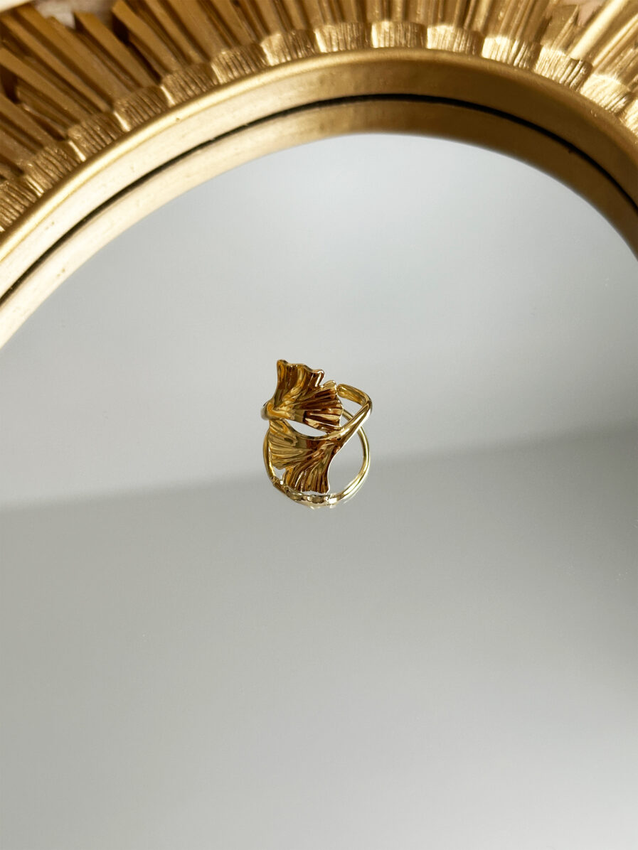 Bague ELOWEN dorée, style chic et moderne posé sur un miroir.