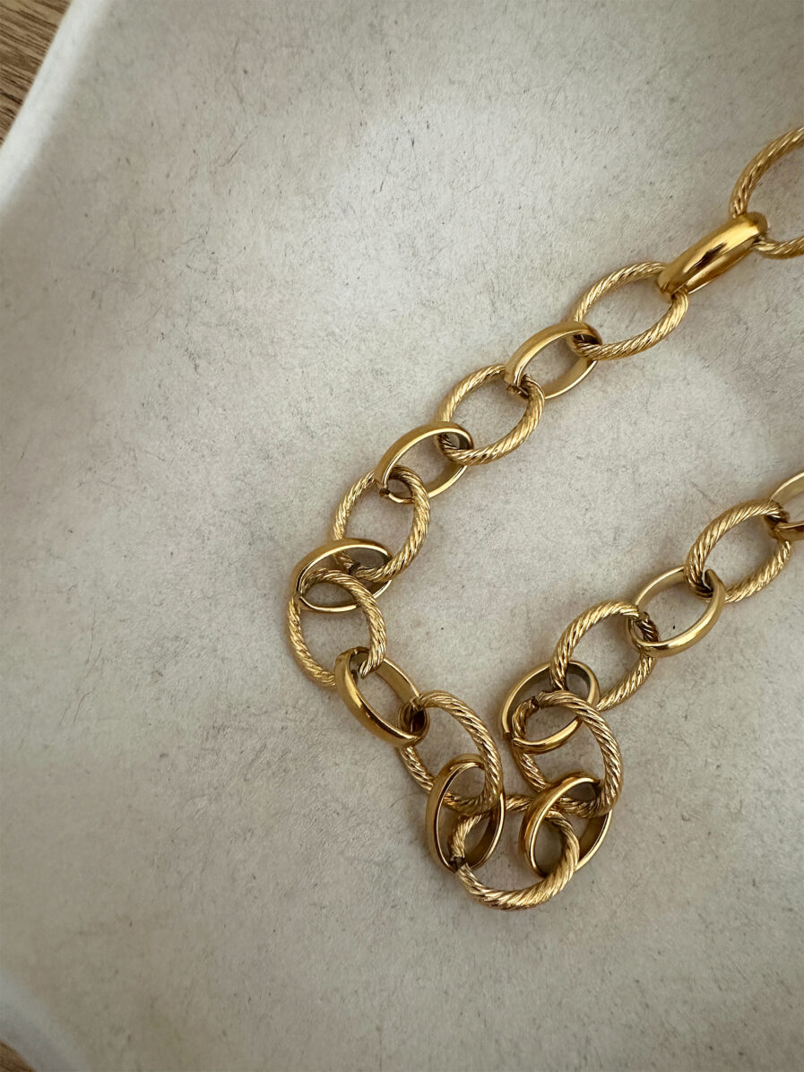 Le collier Carméla est le bijou intemporel qui traverse les saisons sans jamais perdre de son éclat. Ses maillons dorés texturés en acier inoxydable lui donnent une allure à la fois moderne et classique, idéale pour toutes celles qui aiment les pièces fortes et élégantes. Grâce à son design chic et minimaliste, Carméla se porte avec absolument tout ! Matière : acier inoxydable Longueur : 20 cm Fermoir toggle pratique et stylé